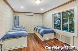 bedroom featuring dark hardwood / wood-style floors, crown molding, and a wall mounted AC