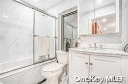 full bathroom featuring shower / bath combination with glass door, vanity, and toilet