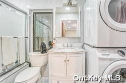 bathroom featuring stacked washer and dryer, vanity, and toilet