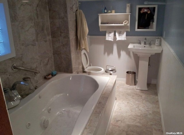 bathroom featuring tiled bath and toilet