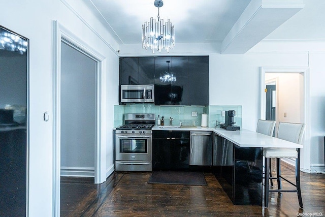 kitchen with pendant lighting, dark hardwood / wood-style floors, a kitchen bar, kitchen peninsula, and stainless steel appliances