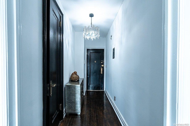 hall with dark hardwood / wood-style floors and an inviting chandelier