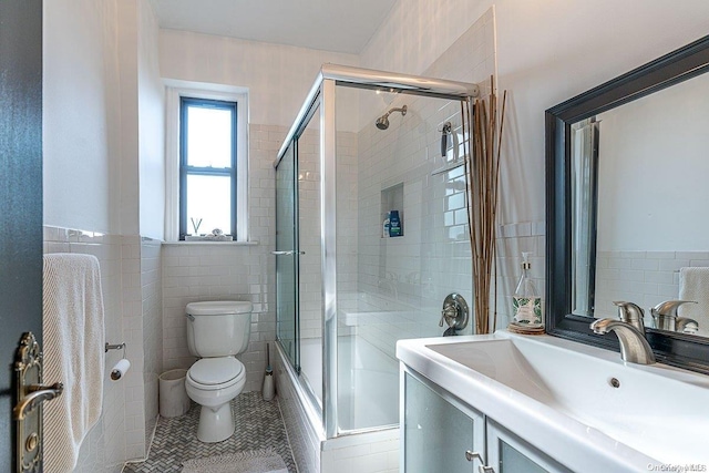 full bathroom featuring tile patterned floors, toilet, shower / bath combination with glass door, and tile walls