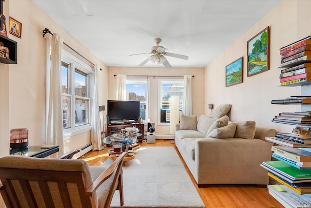 living room featuring light hardwood / wood-style floors, baseboard heating, and ceiling fan