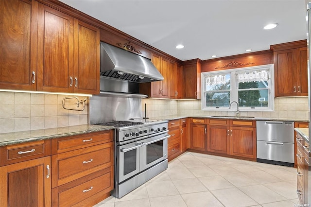 kitchen featuring light stone countertops, sink, wall chimney exhaust hood, backsplash, and appliances with stainless steel finishes