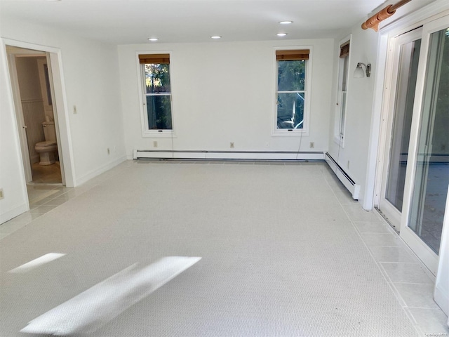 carpeted spare room with a baseboard heating unit