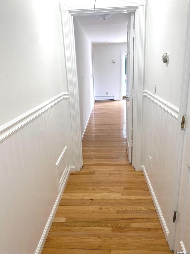 hall with light wood-type flooring and a baseboard heating unit