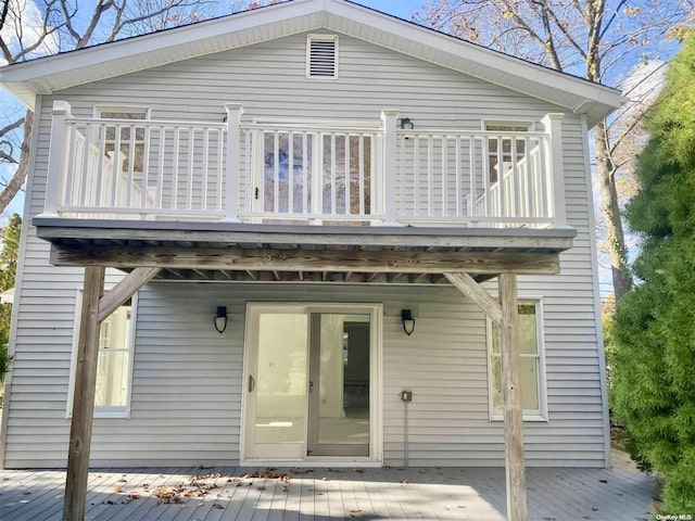 rear view of house featuring a wooden deck and a balcony