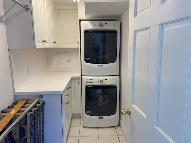 laundry room with cabinets, light tile patterned floors, and stacked washer and dryer