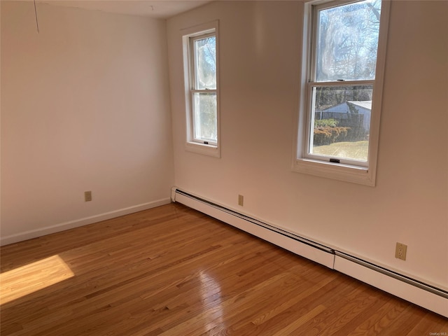 empty room with baseboard heating and light hardwood / wood-style flooring