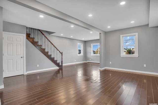 unfurnished living room with baseboard heating and dark wood-type flooring