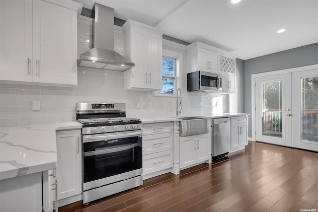 kitchen with french doors, tasteful backsplash, wall chimney exhaust hood, stainless steel appliances, and white cabinets