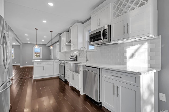 kitchen with light stone countertops, dark hardwood / wood-style flooring, stainless steel appliances, decorative light fixtures, and white cabinetry