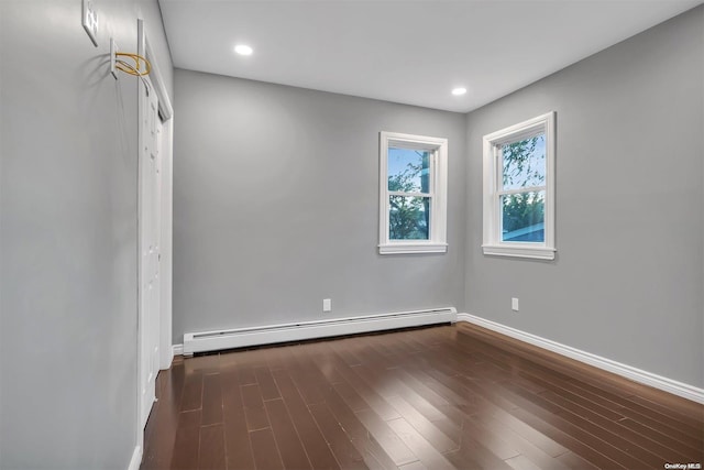 unfurnished room with dark hardwood / wood-style floors and a baseboard heating unit