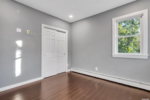 empty room featuring dark hardwood / wood-style flooring and a baseboard heating unit