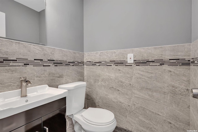 bathroom featuring vanity, toilet, and tile walls