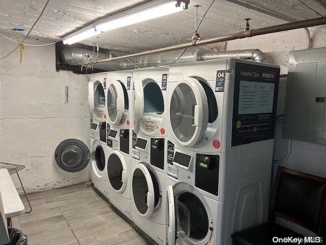 washroom with washer and dryer, stacked washer and dryer, electric panel, and light hardwood / wood-style flooring