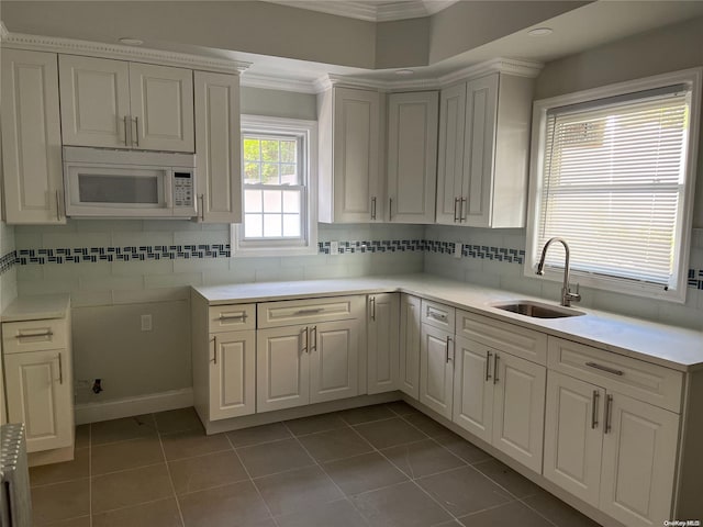 kitchen featuring tile patterned floors, white cabinetry, ornamental molding, and sink