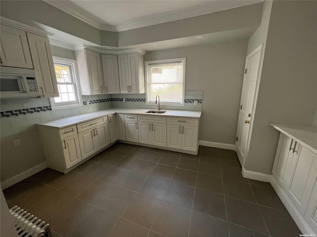 kitchen with plenty of natural light, dark tile patterned floors, white cabinetry, and sink