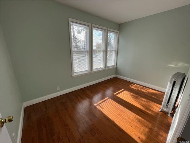 spare room with radiator and dark wood-type flooring