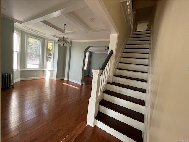 staircase with radiator, coffered ceiling, beamed ceiling, crown molding, and wood-type flooring