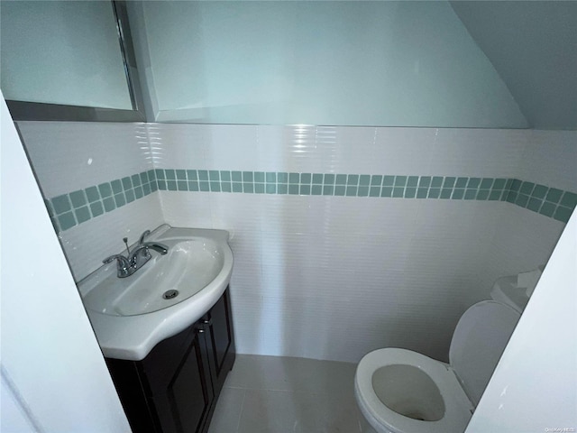 bathroom with tile patterned floors, vanity, toilet, and tile walls