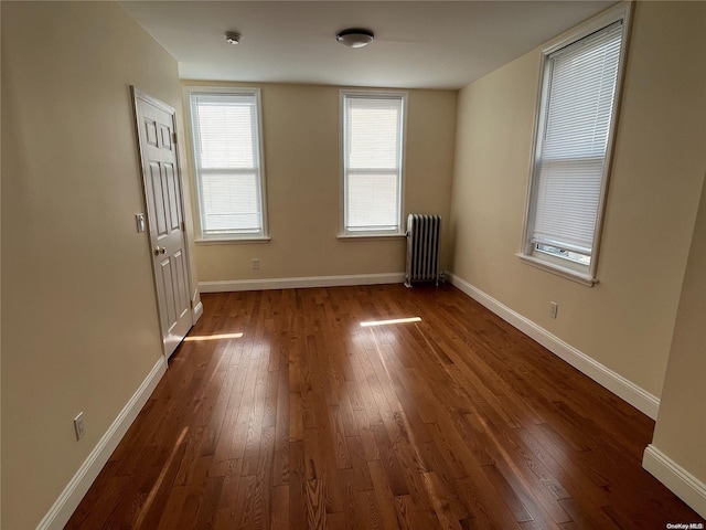 empty room featuring dark hardwood / wood-style flooring and radiator heating unit