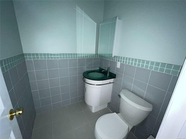 bathroom featuring tile patterned flooring, vanity, toilet, and tile walls