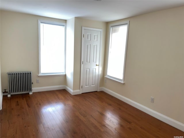 unfurnished room featuring dark hardwood / wood-style flooring, plenty of natural light, and radiator