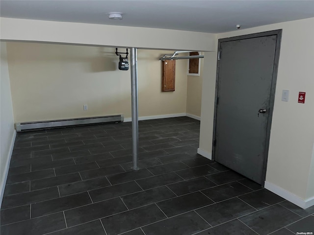 basement featuring a baseboard radiator and dark tile patterned floors