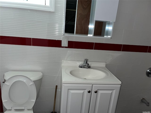 bathroom featuring vanity, tile walls, and toilet