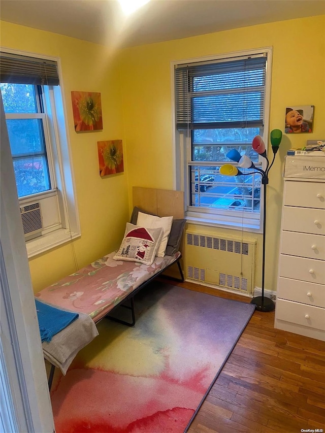 bedroom featuring radiator, cooling unit, and dark wood-type flooring