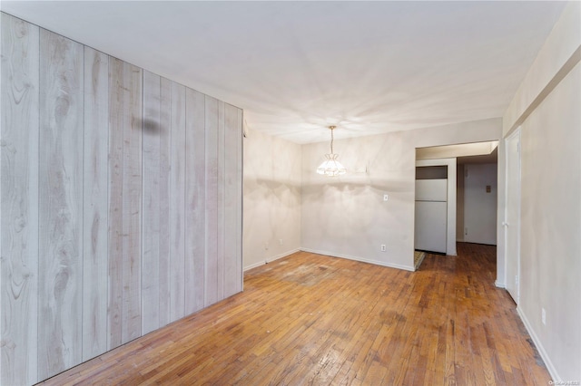 empty room with hardwood / wood-style floors and wooden walls