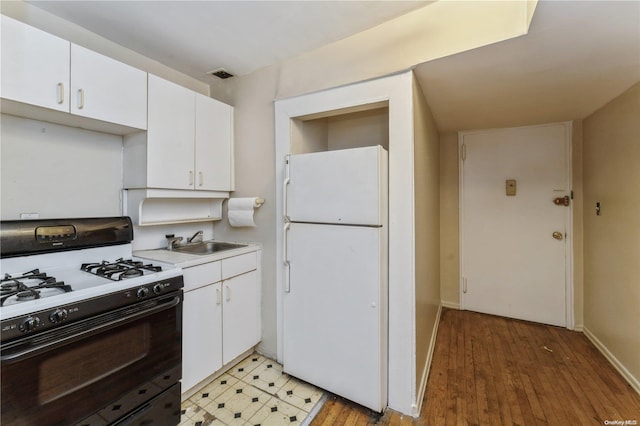 kitchen with white cabinetry, sink, black gas range oven, light hardwood / wood-style flooring, and white fridge