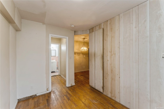 empty room featuring dark hardwood / wood-style floors, an inviting chandelier, and wooden walls