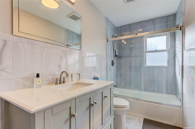 full bathroom featuring vanity, toilet, tile walls, and enclosed tub / shower combo