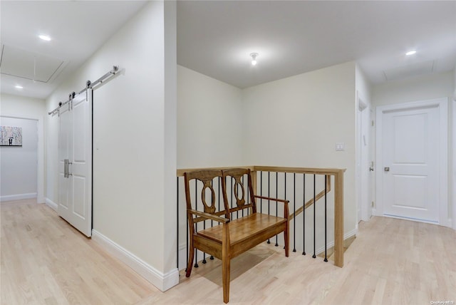 hallway with a barn door and light hardwood / wood-style floors