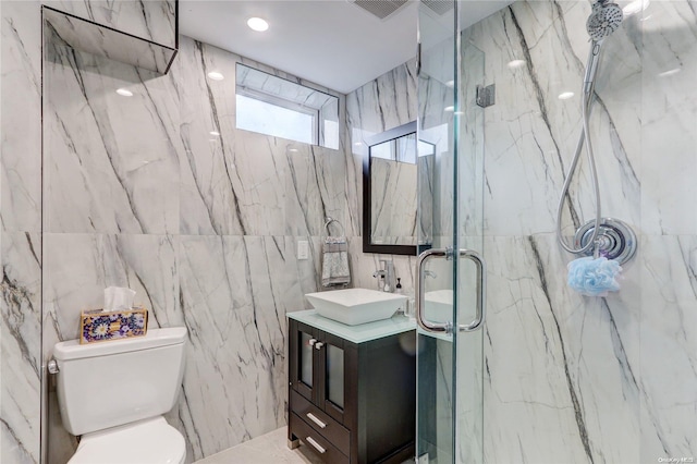 bathroom featuring a shower with door, vanity, tile walls, and toilet