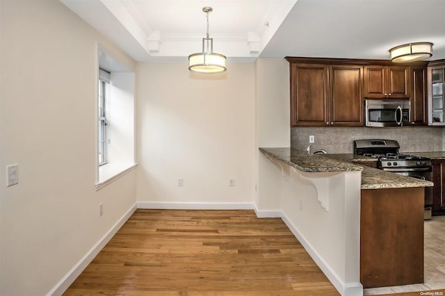 kitchen featuring decorative backsplash, black range with gas stovetop, crown molding, decorative light fixtures, and light hardwood / wood-style flooring