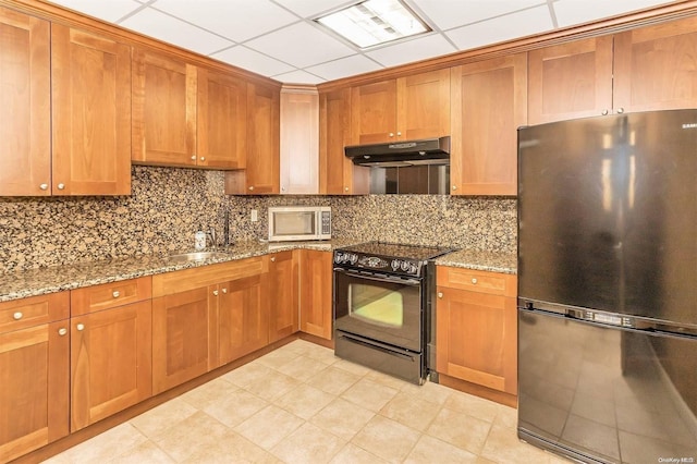 kitchen with a drop ceiling, backsplash, sink, light stone counters, and stainless steel appliances