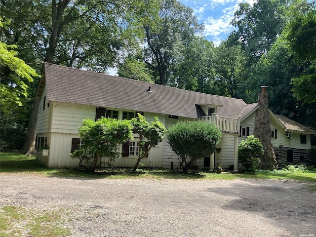 143 Piping Rock Rd, Locust Valley, NY 11560 - view of front of home with roof with shingles, a chimney, and view of wooded area