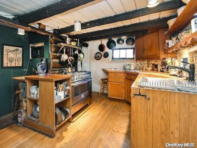 bar featuring beamed ceiling, high end stove, sink, and light hardwood / wood-style flooring