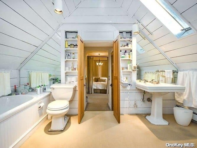 bathroom with toilet, a tub to relax in, wooden walls, and vaulted ceiling