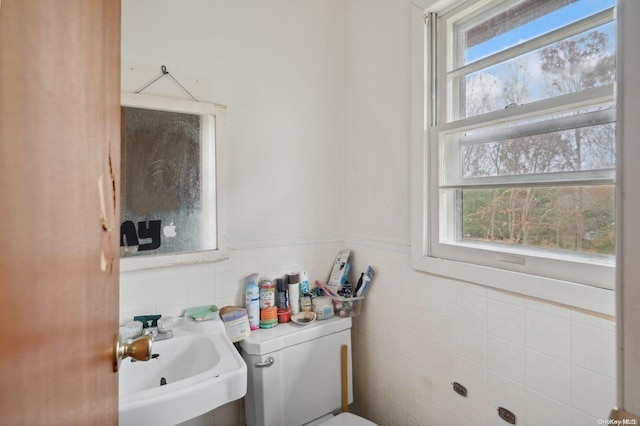 bathroom featuring sink, tile walls, and toilet