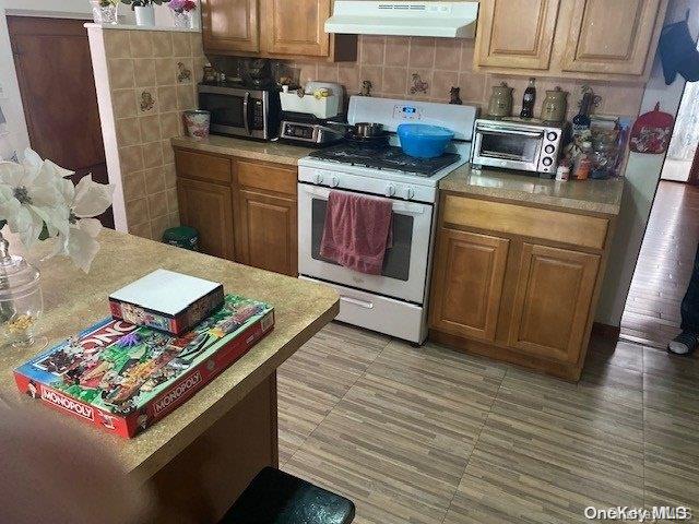 kitchen with backsplash and white range with gas cooktop