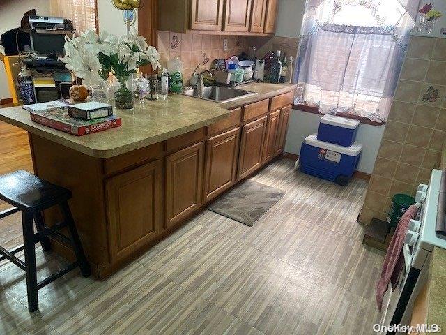 kitchen featuring a kitchen breakfast bar, tasteful backsplash, tile walls, and sink