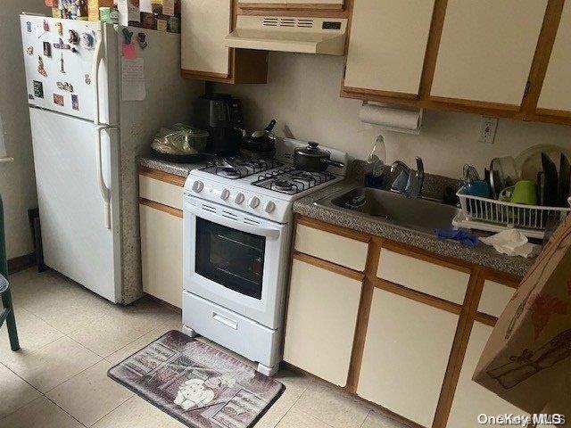 kitchen with sink, white appliances, and range hood