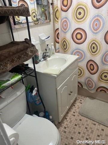 bathroom featuring a shower with shower curtain, vanity, and toilet