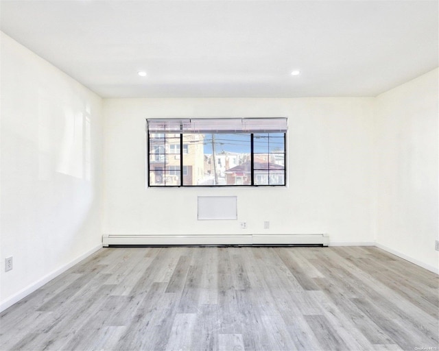 unfurnished room with light hardwood / wood-style floors and a baseboard heating unit