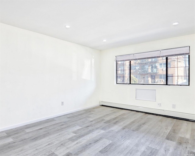 unfurnished room featuring light wood-type flooring and baseboard heating